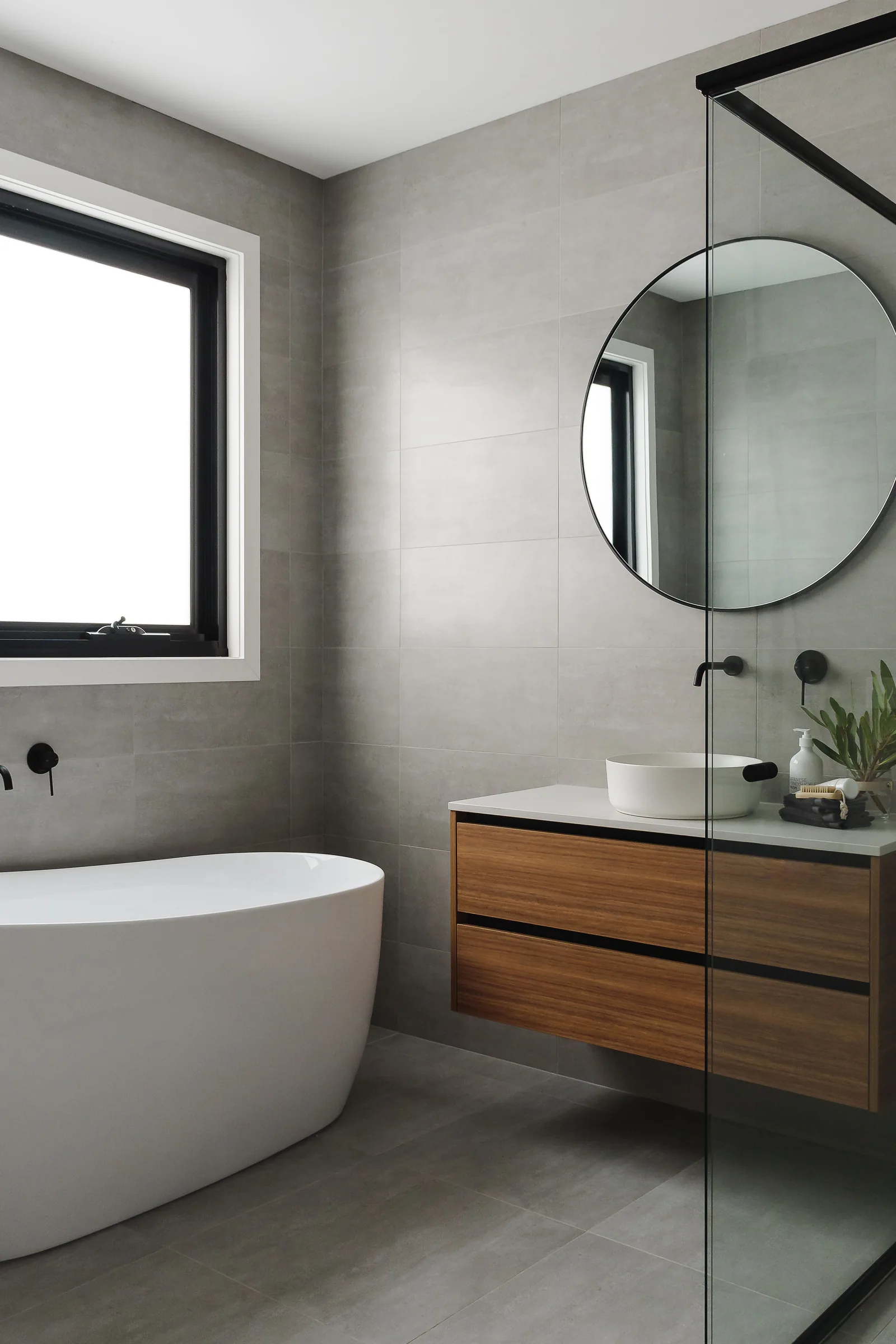 Freestanding bath with grey wall tiles and timber detail